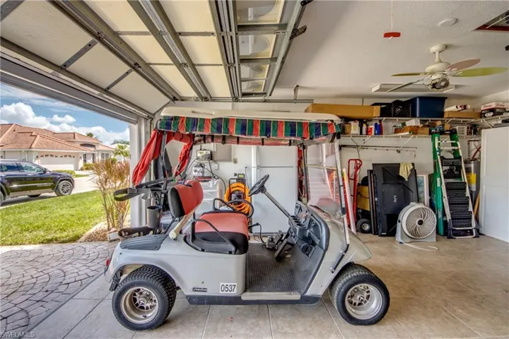 Garage with an automatic overhead door, ceiling fan, and built-in shelving