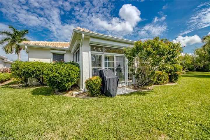 Expansive green lawn with mature landscaping, a tiled patio, and sliding glass doors