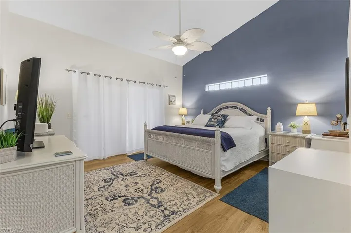 Bedroom with wood finished floors, a ceiling fan, and high vaulted ceiling