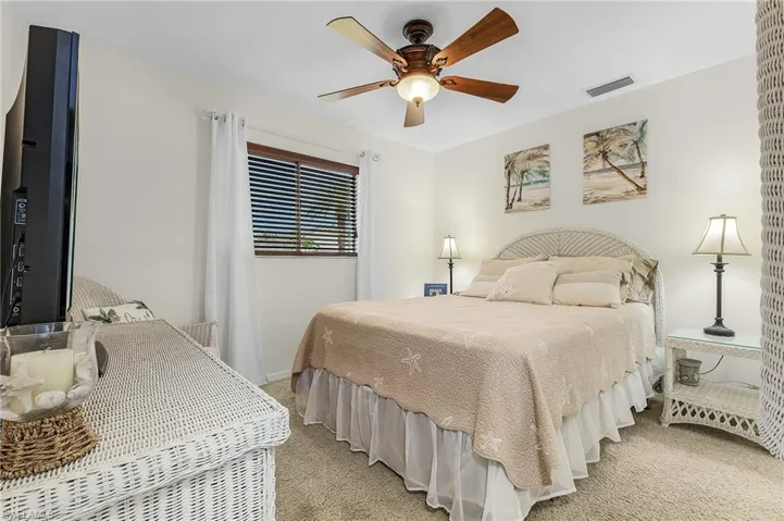 Bedroom featuring light colored carpet, baseboards, and a ceiling fan