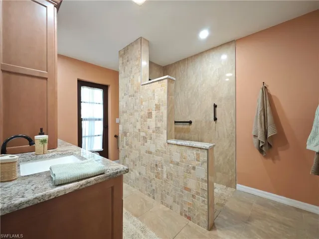 Bathroom with tile patterned floors, vanity, and tiled shower