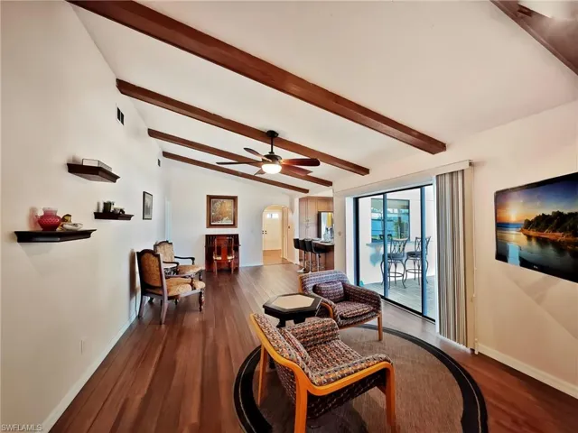 Living room featuring vaulted ceiling with beams, dark hardwood / wood-style floors, and ceiling fan