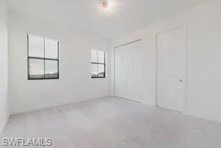 Unfurnished bedroom with light colored carpet and a closet