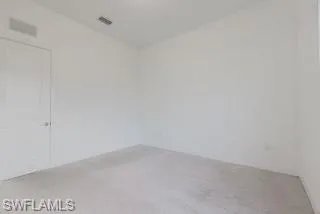 Unfurnished room with light colored carpet and baseboards