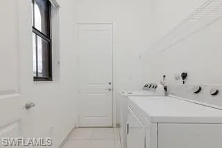Laundry room with washing machine and clothes dryer and light tile patterned floors