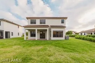 Back of property featuring a lawn, a patio area, and a tile roof
