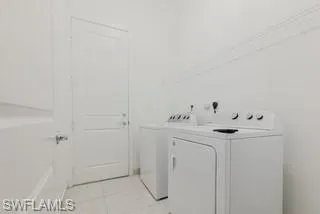 Laundry area featuring independent washer and dryer and light tile patterned floors