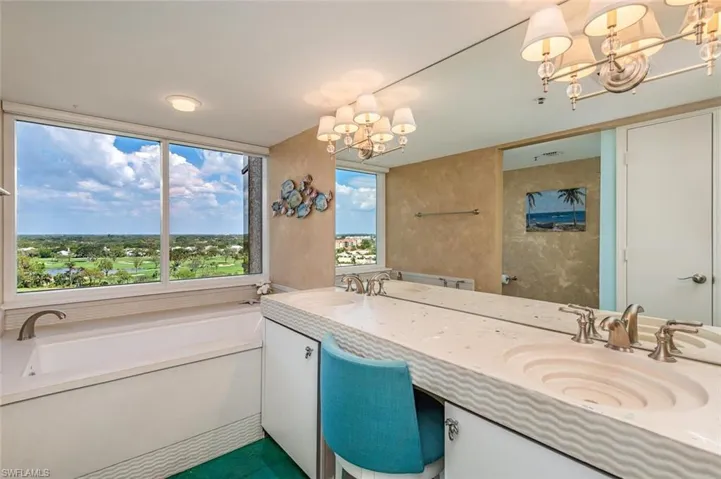 Bathroom with a chandelier, double vanity, and a bath