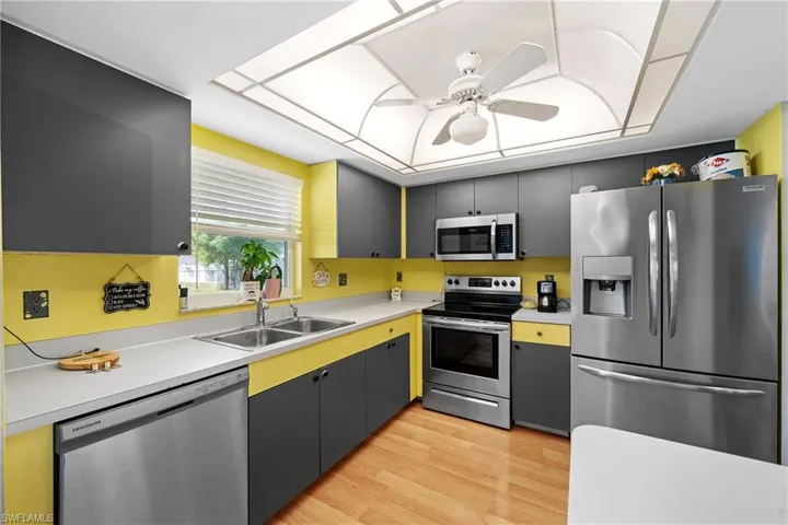 Kitchen with light hardwood / wood-style floors, stainless steel appliances, ceiling fan, sink, and gray cabinets
