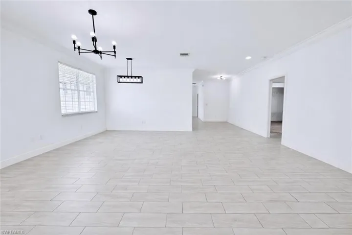 Entry and living room featuring crown molding, tiled floors, and large windows providing ample natural lighting