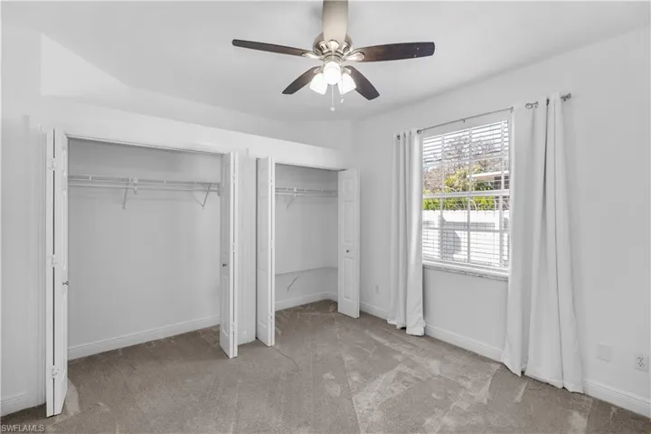2nd bedroom featuring double closets, light carpet, and a ceiling fan with tons of natural lighting