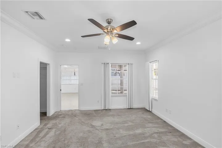 Master bedroom with light carpet, a ceiling fan, crown molding, recessed lighting, and a healthy amount of natural light