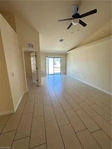 Spare room featuring vaulted ceiling, ceiling fan, and light tile patterned floors