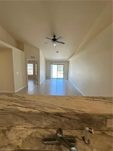 Unfurnished room with ceiling fan, vaulted ceiling, and light tile patterned floors