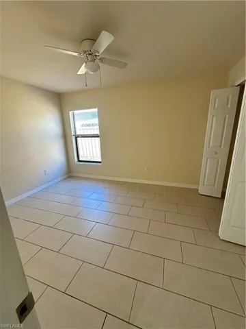 Empty room with ceiling fan and light tile patterned floors