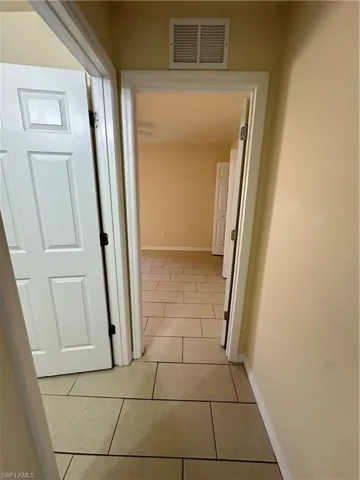 Hall with baseboards and light tile patterned floors