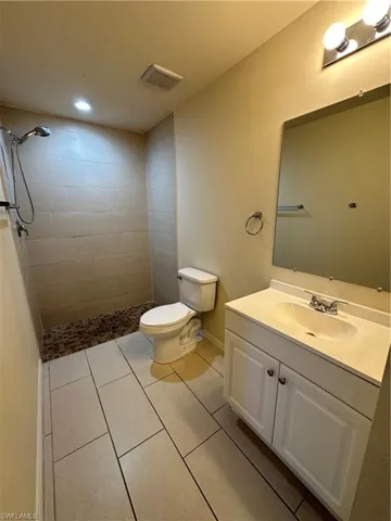 Full bath featuring vanity, light tile patterned floors, tiled shower, and recessed lighting