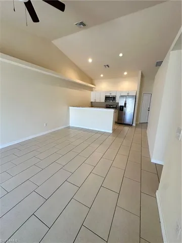 Unfurnished living room with lofted ceiling, recessed lighting, a ceiling fan, and light tile patterned floors