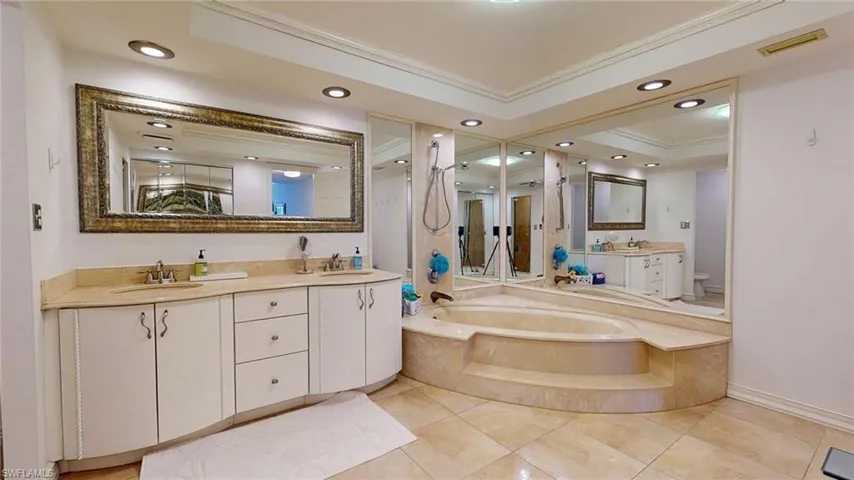Bathroom featuring double vanity, crown molding, recessed lighting, a bath, and light tile patterned flooring