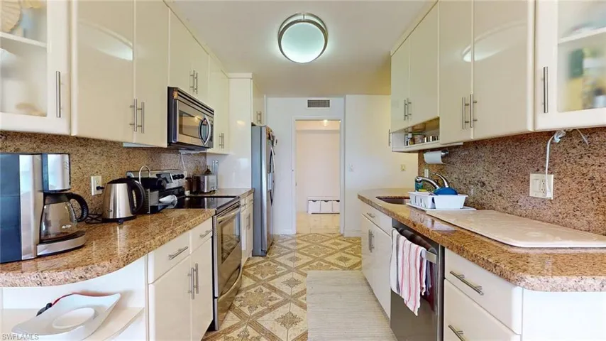 Kitchen with decorative backsplash, glass insert cabinets, appliances with stainless steel finishes, and open shelves