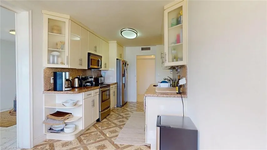 Kitchen with glass insert cabinets, backsplash, appliances with stainless steel finishes, and white cabinets