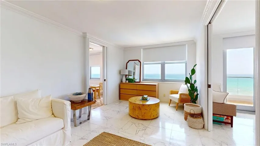 Living area with crown molding, marble look tile flooring, and a water view