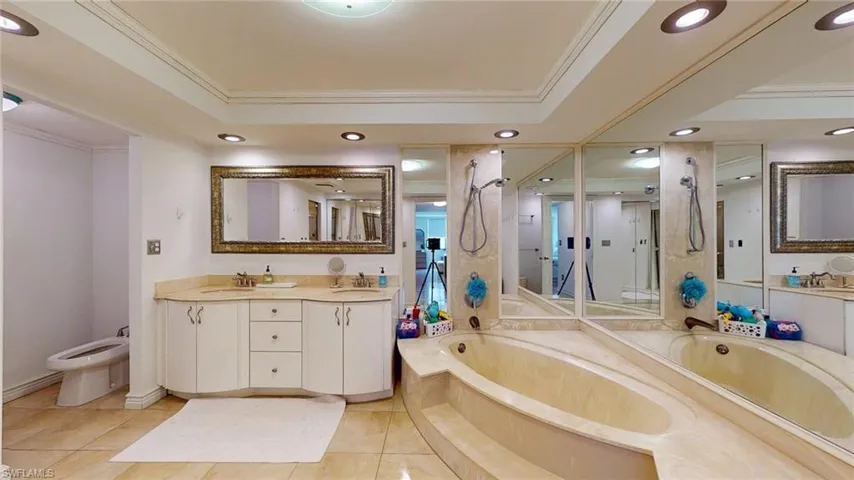 Bathroom with crown molding, double vanity, a bath, recessed lighting, and light tile patterned flooring