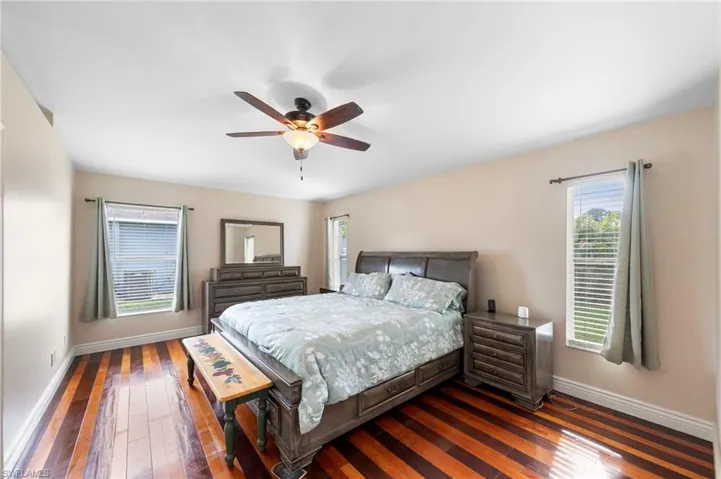 Spacious room featuring wood-finish flooring, light-toned wall paint, and a ceiling fan with integrated lighting