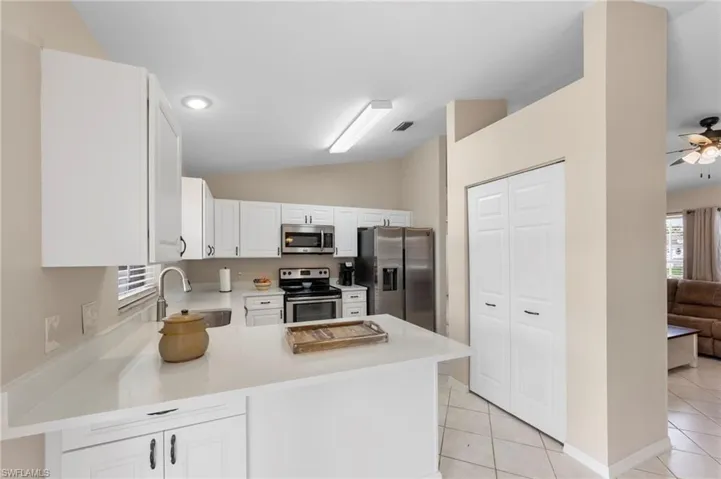 Kitchen featuring white cabinetry, light-toned countertops, stainless steel appliances, and tile flooring