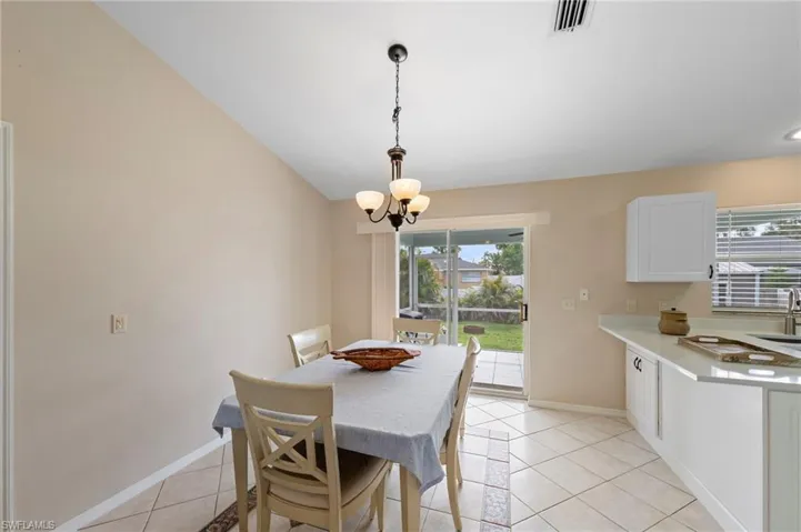 Open concept dining area with vaulted ceilings, tile flooring, and a contemporary chandelier