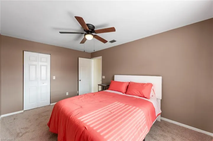 Bedroom featuring a ceiling fan with light fixture, neutral wall paint, and white trim