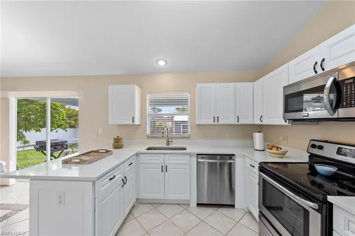 Contemporary kitchen featuring white cabinetry, light countertops, and stainless steel appliances