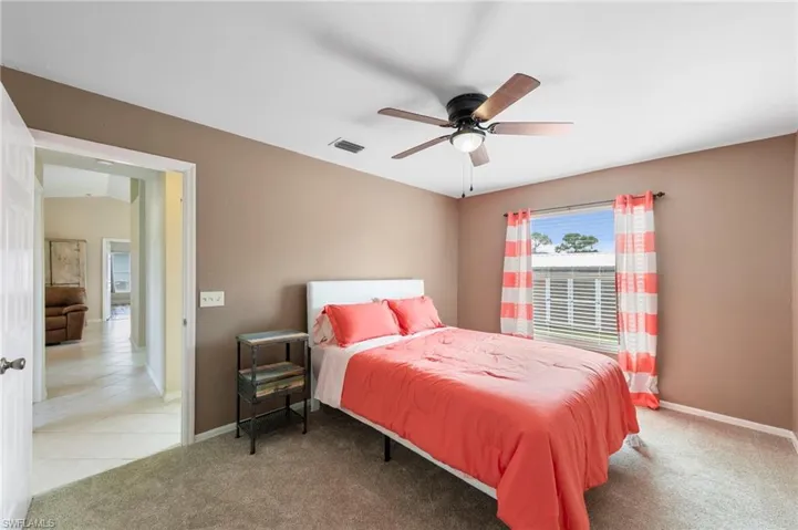 Carpeted room featuring a ceiling fan with integrated lighting, a window with horizontal blinds, and neutral wall tones
