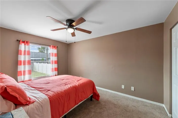 Bedroom featuring a window with white blinds, neutral-toned walls, and a ceiling fan with integrated lighting