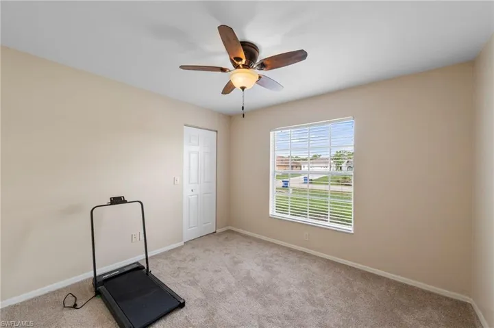 Carpeted room featuring a ceiling fan with light fixture, a window with horizontal blinds, and a bi-fold closet door