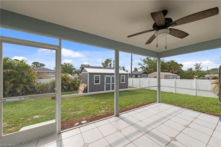 Screened patio with a dark wood-finish ceiling fan and light tile flooring