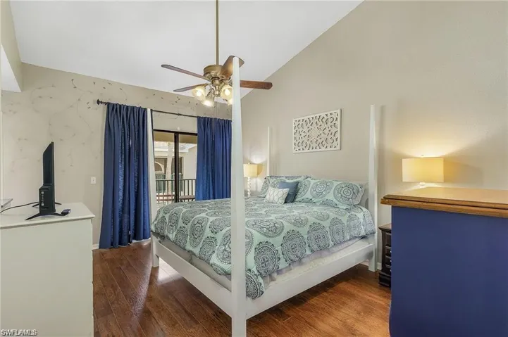 Bedroom with lofted ceiling, wood finished floors, a ceiling fan, and access to outside