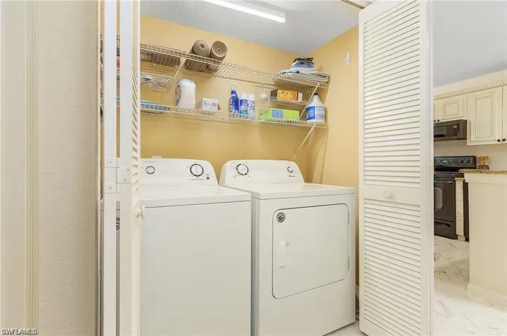 Laundry room with washer and dryer, laundry area, and marble finish floor