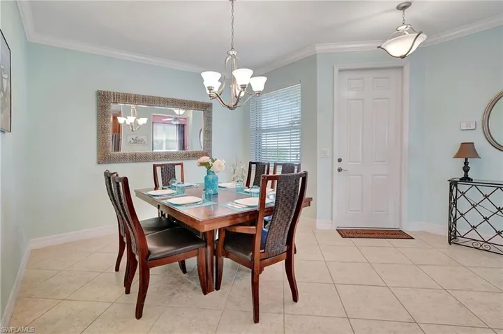 Dining space with ornamental molding, light tile patterned floors, and a chandelier