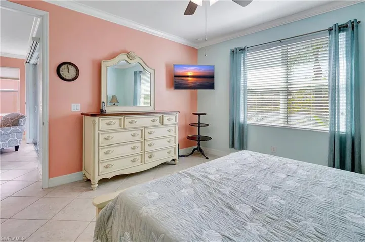 Bedroom with tile patterned flooring, crown molding, and a ceiling fan