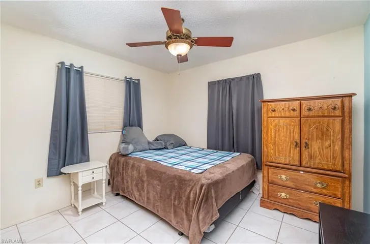 Tiled bedroom featuring ceiling fan and a textured ceiling