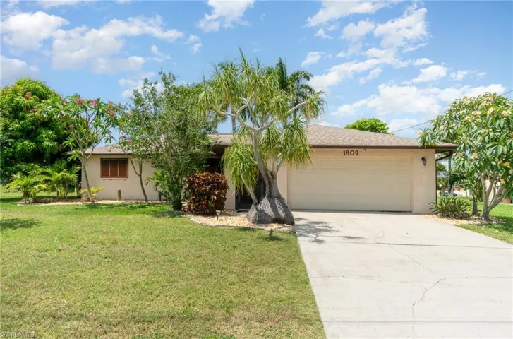 Single story home featuring a garage and a front lawn