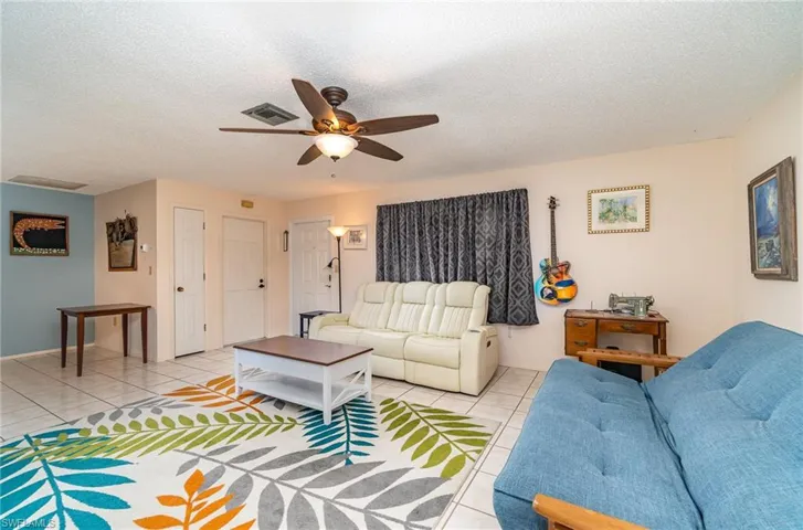 Living room featuring ceiling fan, a textured ceiling, and light tile floors