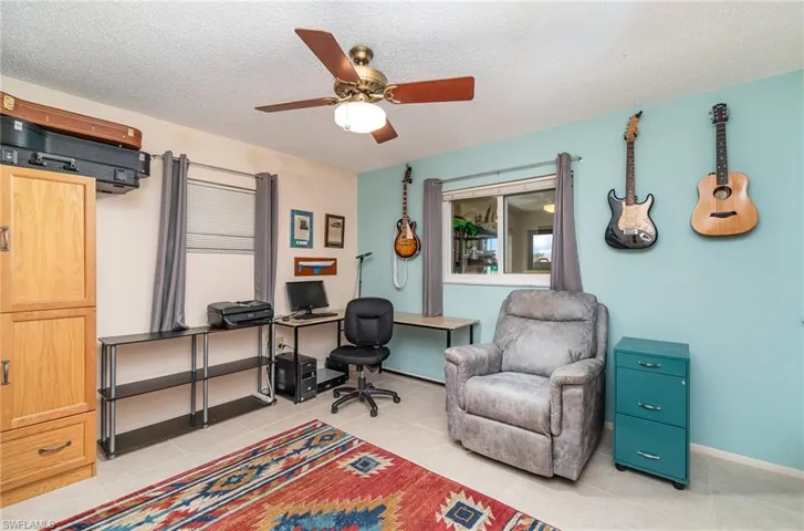 Office area with a textured ceiling, ceiling fan, and light tile floors