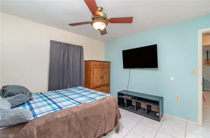 Bedroom with a textured ceiling, ceiling fan, and light tile floors