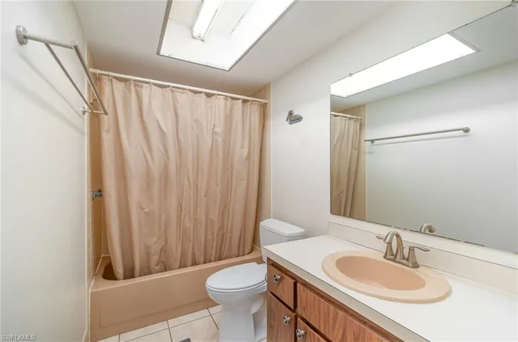 Full bathroom featuring tile floors, shower / bath combination with curtain, large vanity, and toilet