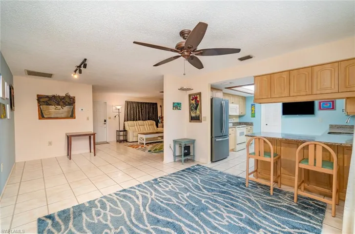 Tiled living room with sink, a textured ceiling, track lighting, and ceiling fan