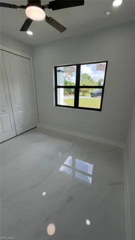 White tile flooring, recessed lighting, ceiling fan, white bi-fold closet doors, and a black-framed window