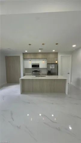 Gleaming white tile flooring throughout, featuring a kitchen island with an integrated sink