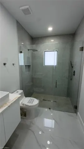 Glass-enclosed shower with a rainfall shower head, wall-mounted shower head, and built-in niche